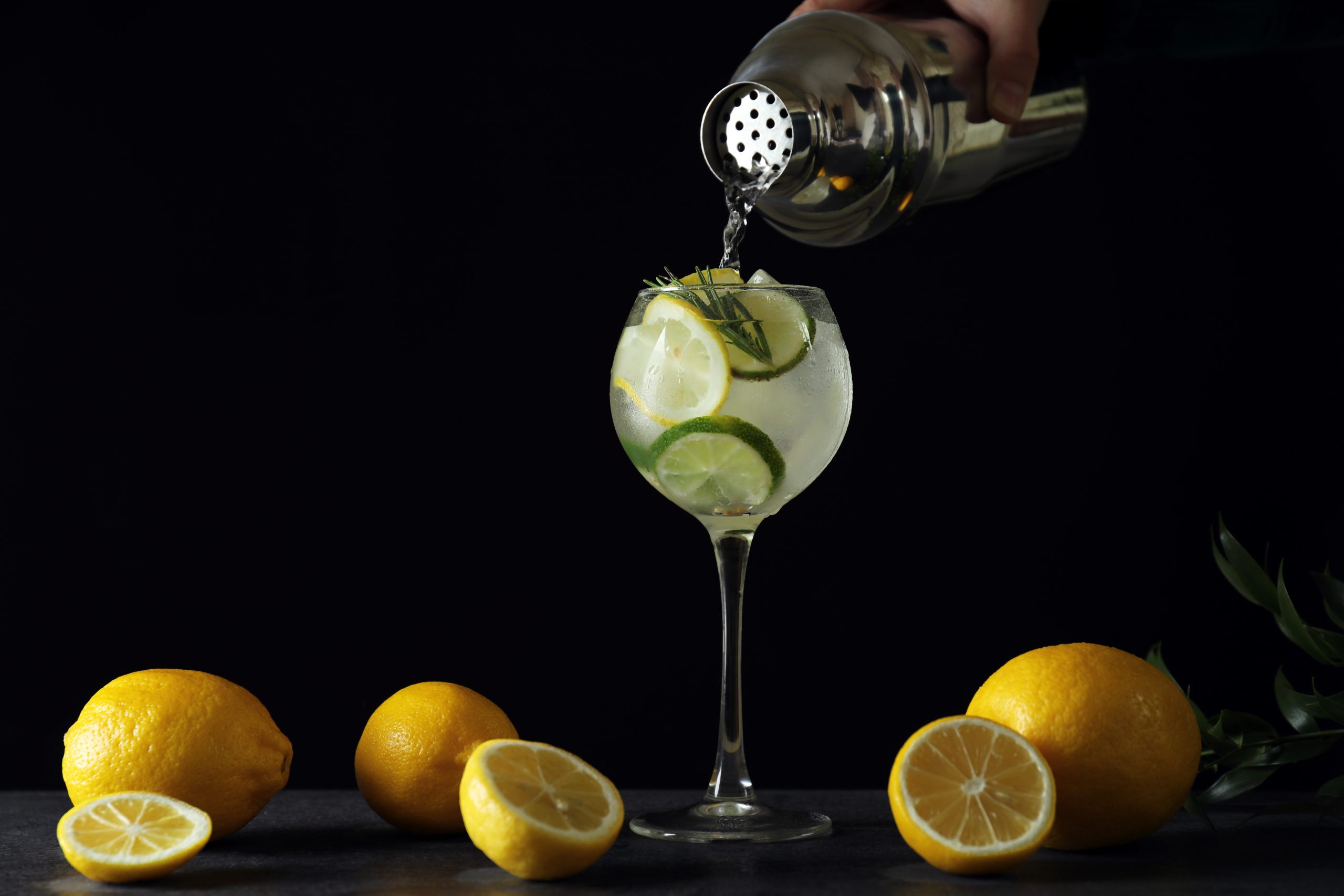 Female hand pour cocktail in glass on dark background